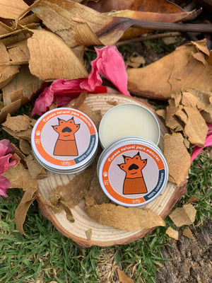 Dos pomadas para mascotas en un trozo de madera y pasto