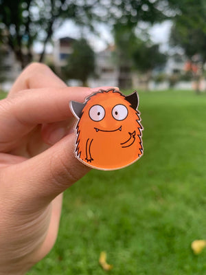 Pin monstruo naranja haciendo el gesto de paz