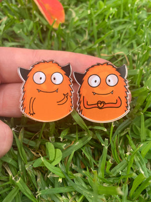 Pines con monstruo naranja saludando con fondo pasto